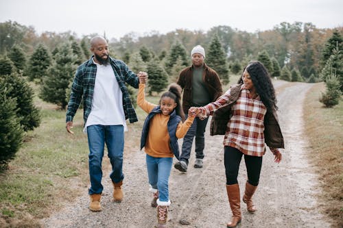 Smiling ethnic family walking on tree farm road