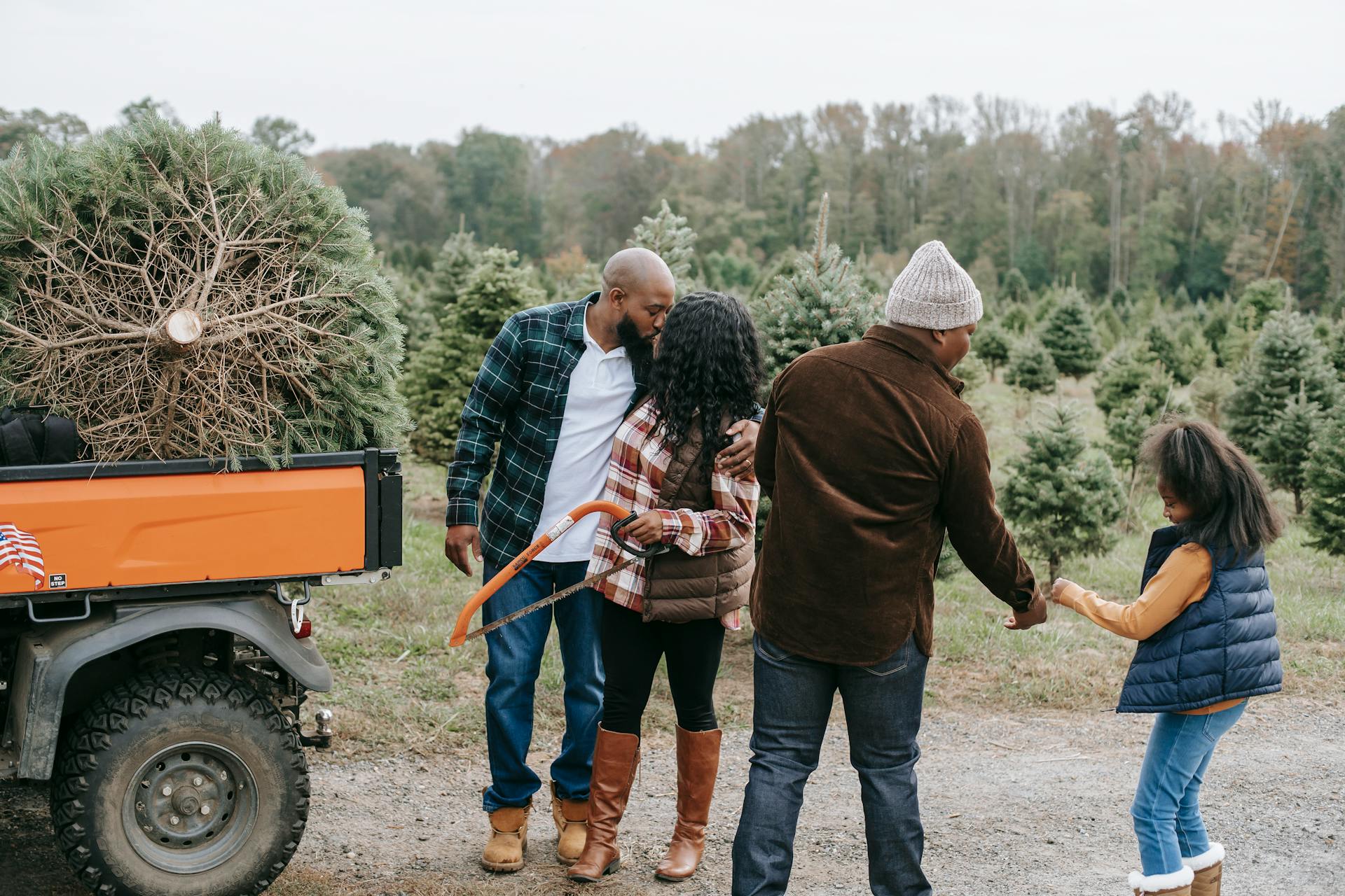 Unrecognizable black parents speaking near teen and girl on roadway with ATV on tree farm