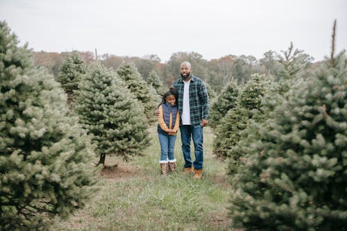 Black father embracing daughter on tree farm