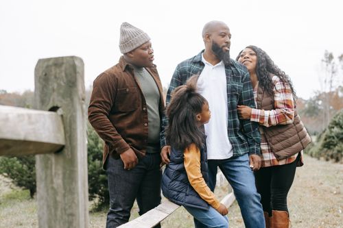 Free Young black parents with son and daughter interacting near wooden fence in countryside under white sky Stock Photo
