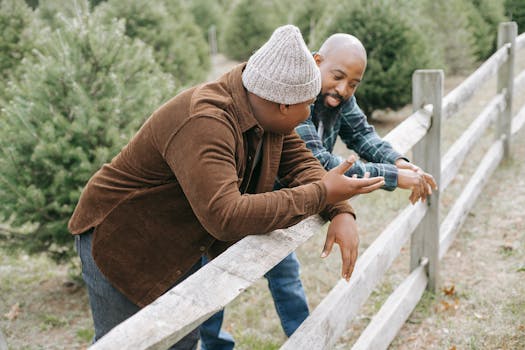 Two men having a casual conversation by a rustic wooden fence outdoors.