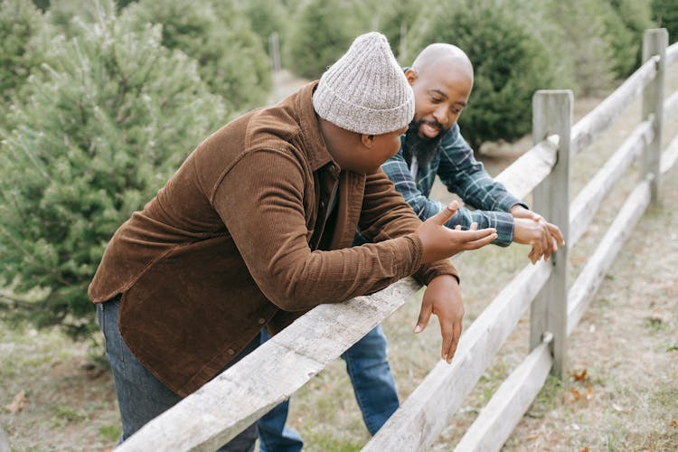 Black Father Talking To Unrecognizable Son Near Fence In Countryside