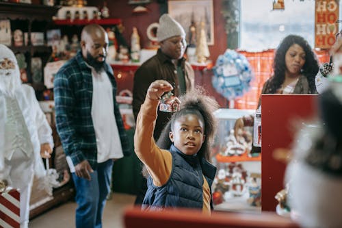 Young African American parents with son and daughter looking for New Year gifts in souvenir shop