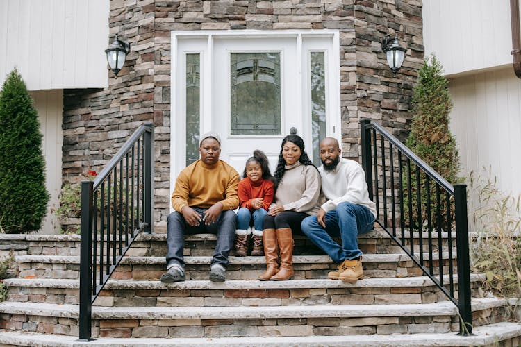 Smiling Black Family On House Stairs In Daylight