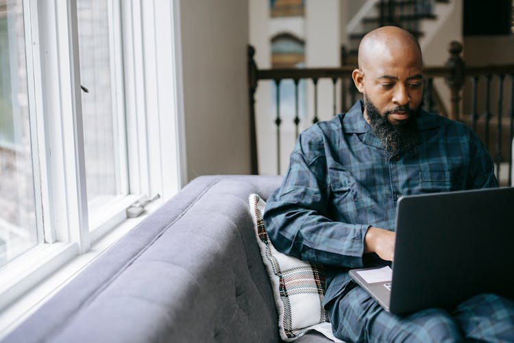 Serious Black Man Using Laptop At Home