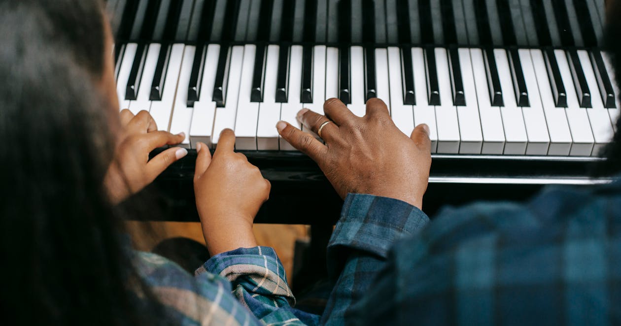 Free From above of crop anonymous African American man playing musical instrument with girl while rehearsing together Stock Photo