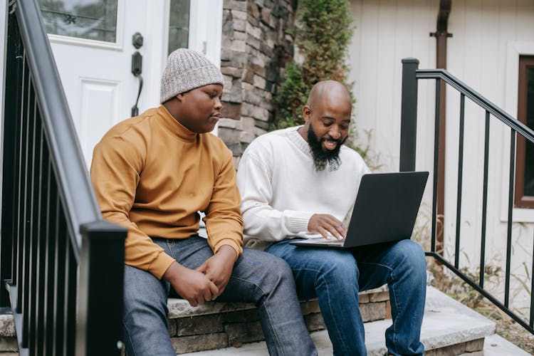 Cheerful Black Businessman Browsing Laptop With Son