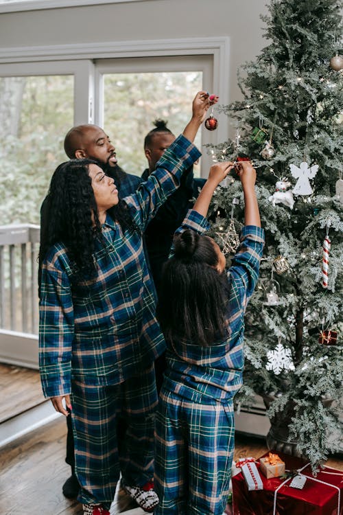 Black family decorating Christmas tree with toys
