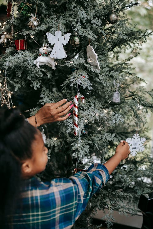 Black girl decorating Christmas tree with mother