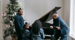 Black family playing piano together in cozy room