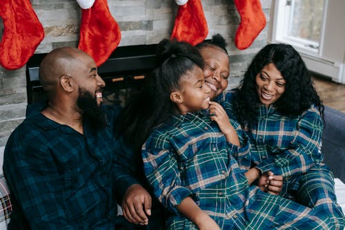 Joyful black family cuddling together on sofa