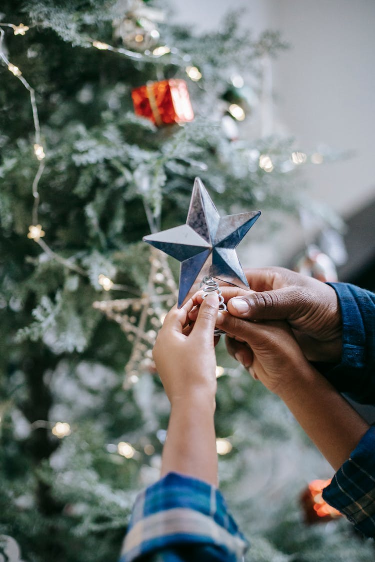 Black Dad Putting Star On Christmas Tree With Child