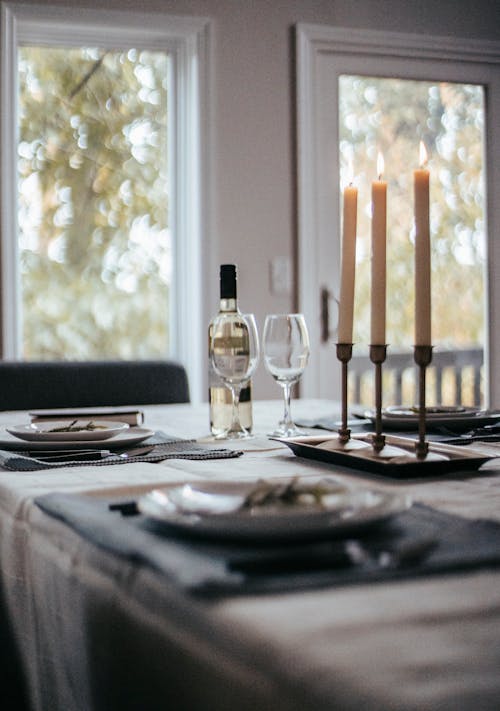 Free Table with various tableware with bottle of wine glasses and candles placed on tablecloth and prepared for event Stock Photo