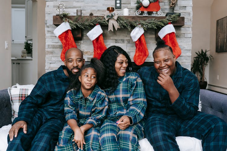 A Family Wearing Checkered Pajamas Sitting On A Couch