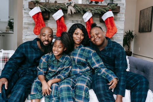 Cheerful African American family wearing similar clothes sitting close at home decorated with Christmas gift socks