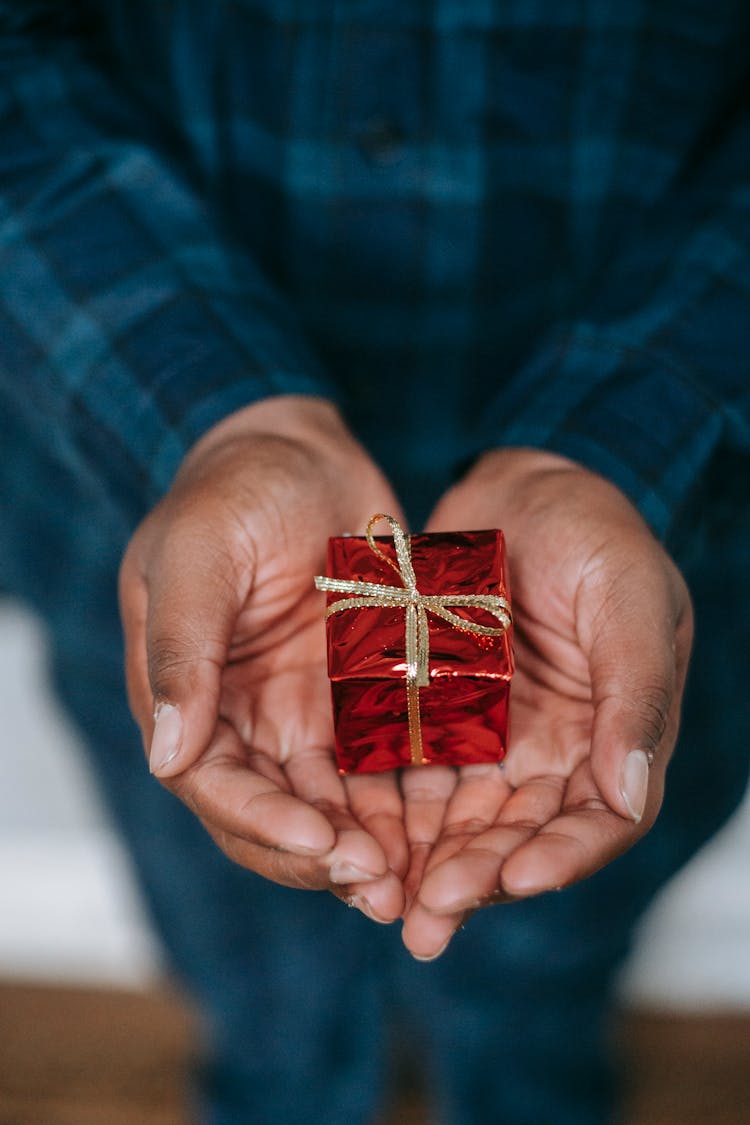 Person Holding Small Present Box With Golden Ribbon