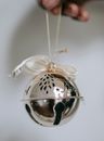 Person holding silver jingle bell with ribbon