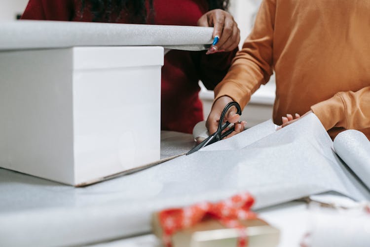 Photo Of A Person's Hands Cutting Wrapping Paper