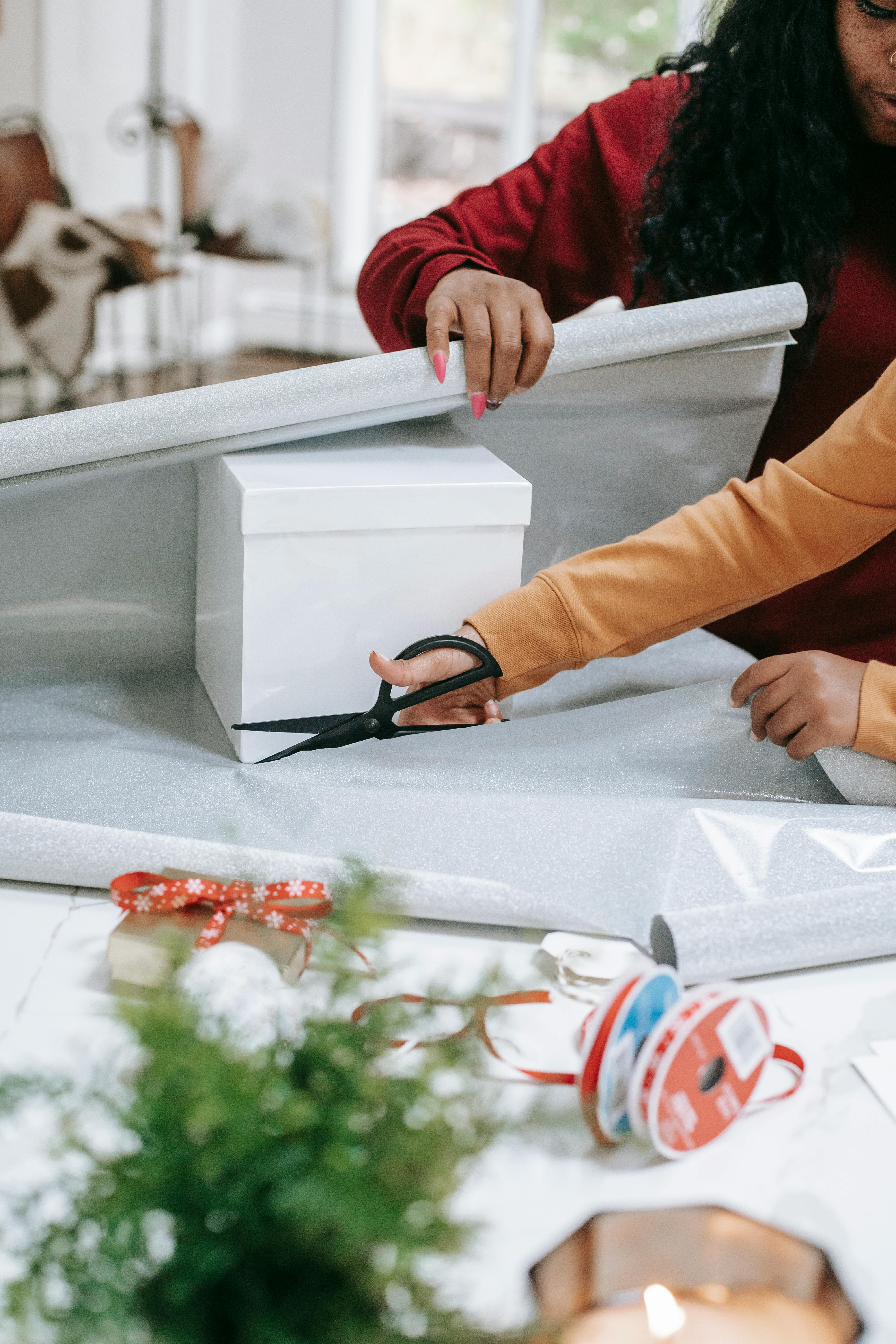 kid cutting paper with black mom for christmas present