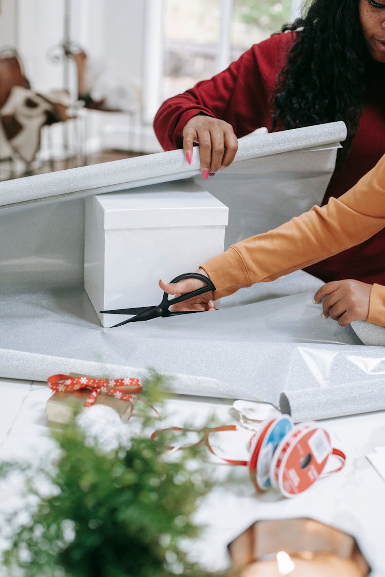 Kid Cutting Paper With Black Mom For Christmas Present