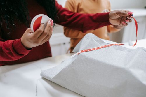 Free Unrecognizable crop African American mother and child preparing Christmas presents together and wrapping with tape Stock Photo