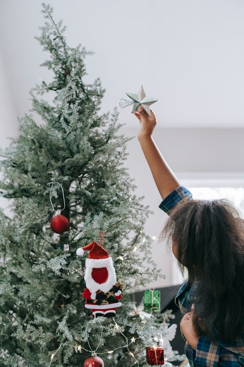 Unrecognizable black girl decorating Christmas tree at home
