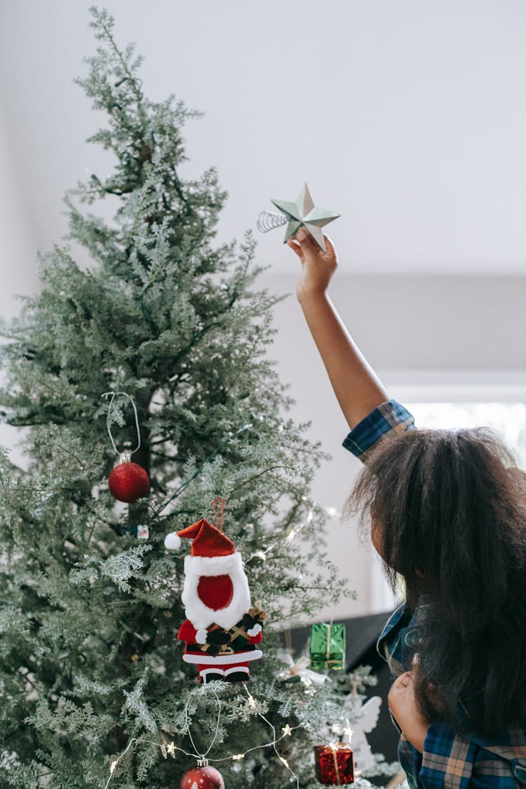 Unrecognizable Black Girl Decorating Christmas Tree At Home