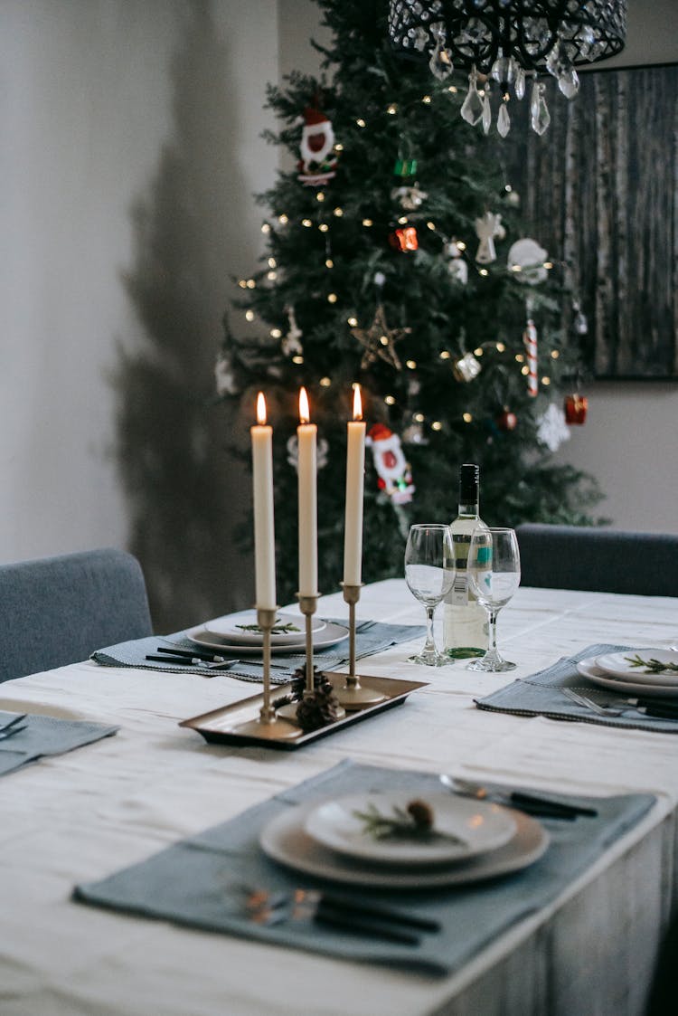 Banquet Table With Burning Candles Near Christmas Tree