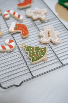 Decorative Christmas cookies shaped like trees, socks, and snowmen on a cooling rack.