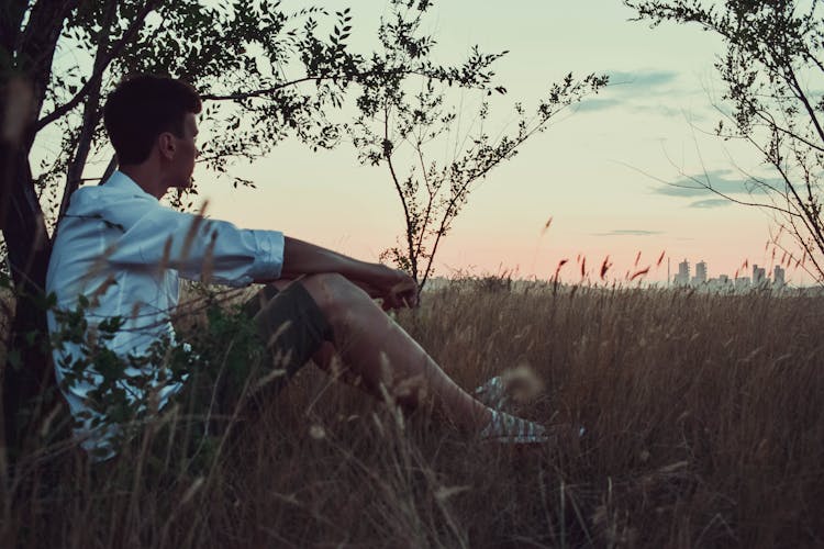 Man Sitting In Grass Field Thinking