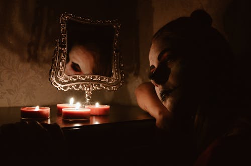 Woman in Halloween Makeup Sitting Next to Burning Candles 