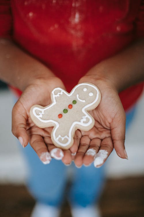 Crop black child showing gingerbread cookie during Christmas holiday