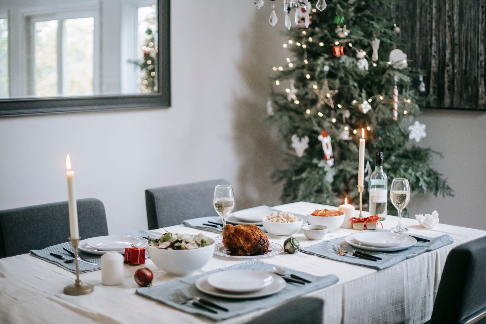 Elegant dining table set for a festive Christmas dinner with a beautifully decorated tree in the background.