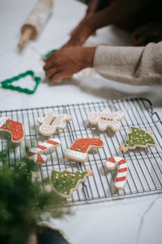 Hands decorating festive gingerbread cookies with icing for Christmas celebration.