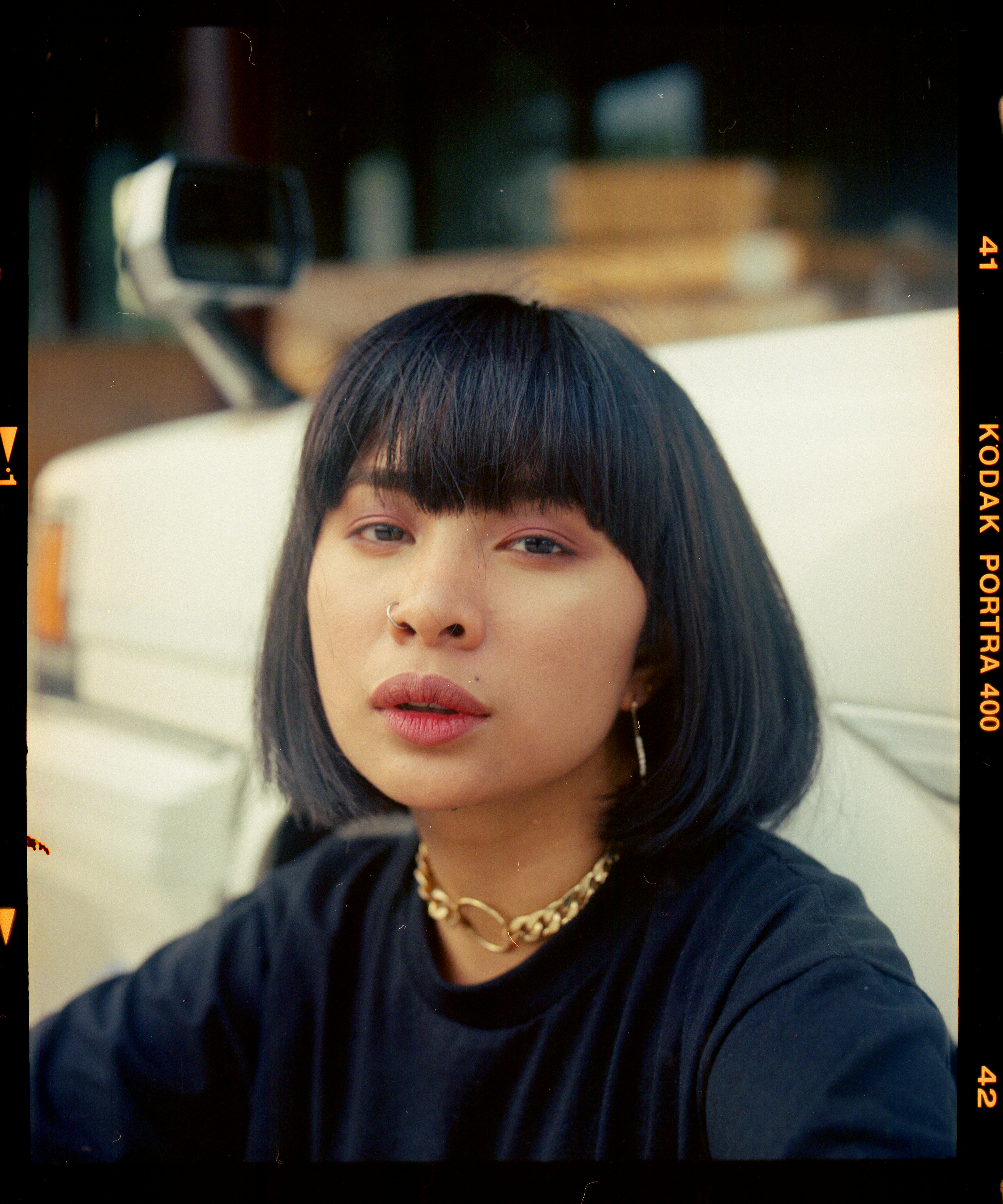 A captivating portrait of a young woman with bangs and a nose piercing, showcasing her unique style.