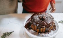 从上方，黑人孩子和匿名家长将糖粉倒在巧克力釉圣诞海绵蛋糕上