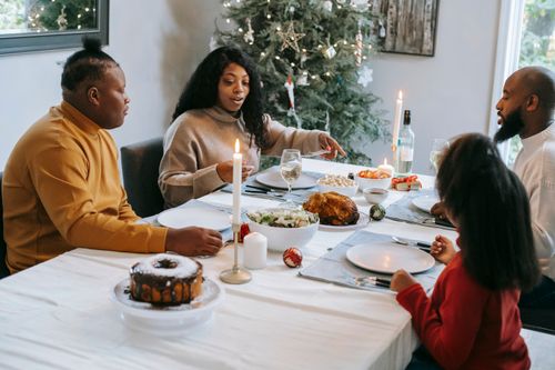 Free Ethnic parents with anonymous daughter and son interacting at table with delicious food while celebrating New Year holiday at home Stock Photo