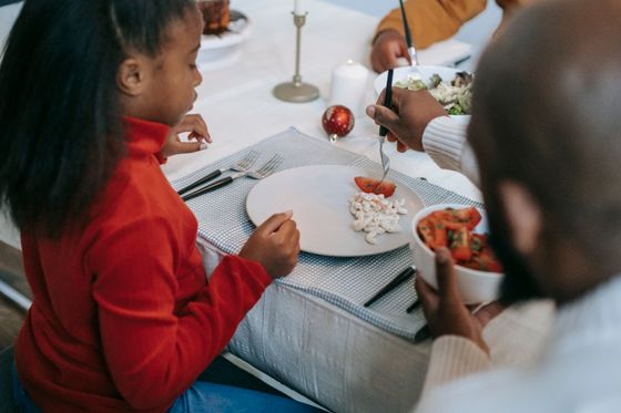 A parent serving salad at the table — photo by Any Lane on Pexels