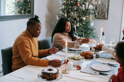 Free Positive African American family with kids having dinner at table with dishes and burning candles while celebrating Christmas at home Stock Photo