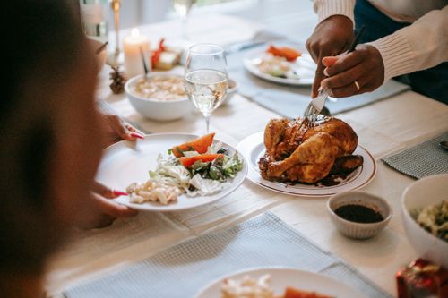 Free A warm family dinner scene featuring a roasted chicken with sides and wine on a table setting. Stock Photo