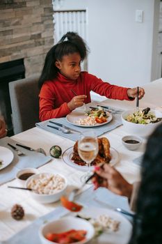 From above of African American preteen girl sitting at festive table with plate while eating delicious food during holiday celebration