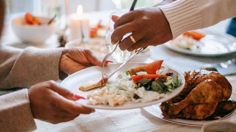 A festive Thanksgiving dinner being served with roast turkey and fresh salad on a table.