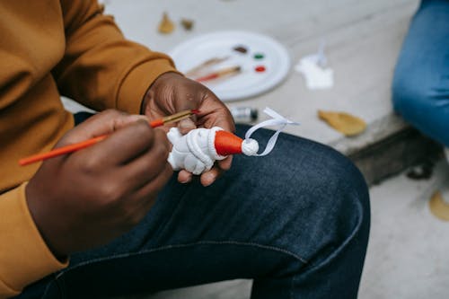 Crop black man painting on toy