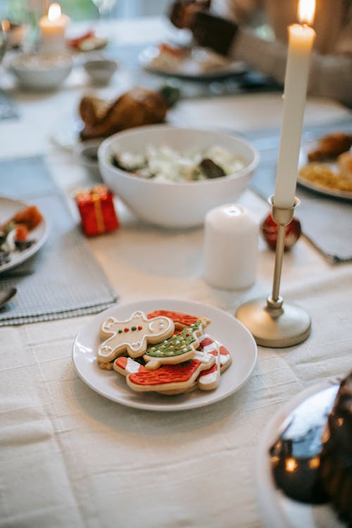 From above of table served with home baked gingerbread with icing placed near candle and bowls with delicious food on blurred background