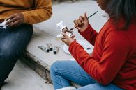 一名非裔美国青少年坐在木楼梯上，用画笔和油漆装饰人物