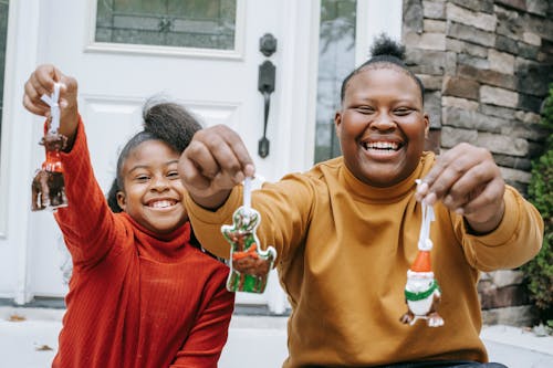 Cheerful smiling black teens demonstrating Christmas decorations