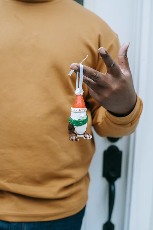 Crop anonymous African American male demonstrating handmade present hanging on ribbon on hand