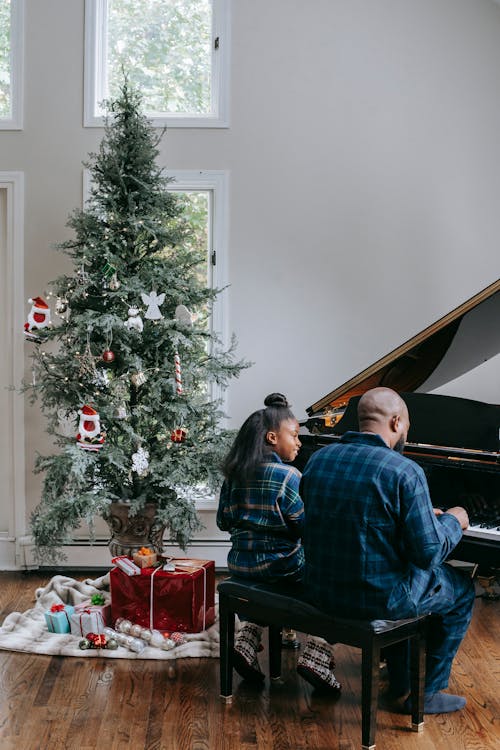 A Father and Her Child Playing a Piano Near a Christmas Tree