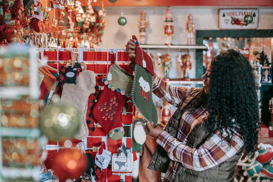 Free Side view of smiling African American female with Xmas sock in shop with decorative baubles and gifts Stock Photo