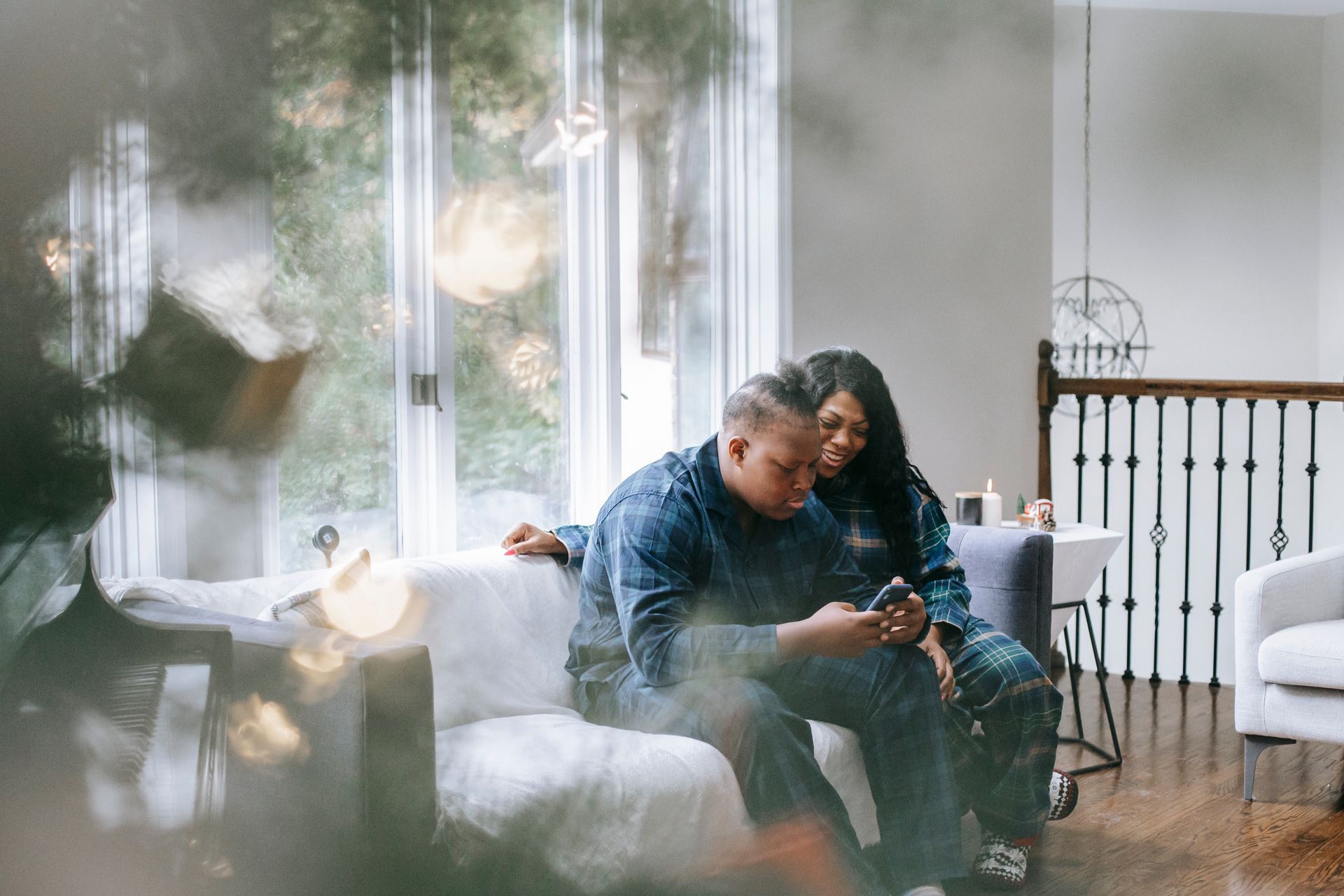 A family enjoys a cozy holiday moment together, browsing on a smartphone by the window.